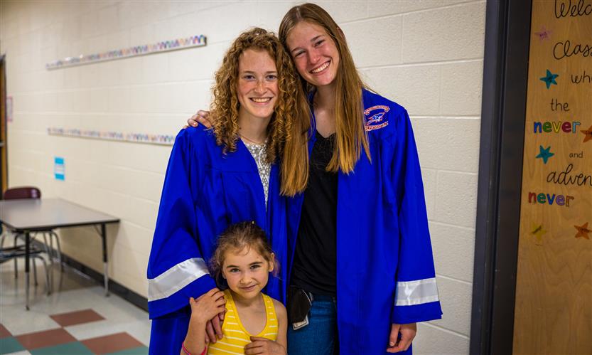 Two seniors smile with a younger sister
